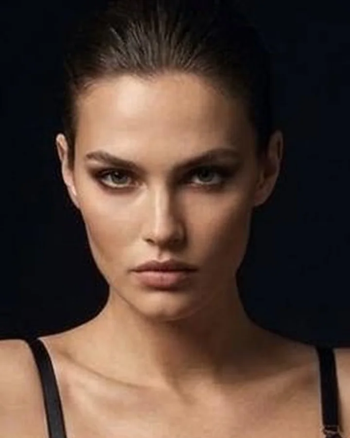 The model's face, hair slicked back, looking straight into the camera.
